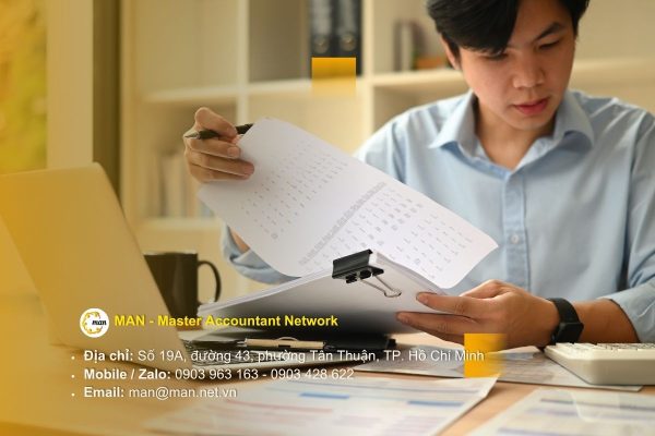 Kiểm toán viên đang xem xét hồ sơ quyết toán vốn đầu tư với biểu đồ và tài liệu tài chính trên bàn