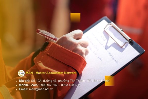 Kiểm toán viên đang kiểm tra sổ sách kế toán và báo cáo tài chính trong quy trình kiểm toán doanh nghiệp